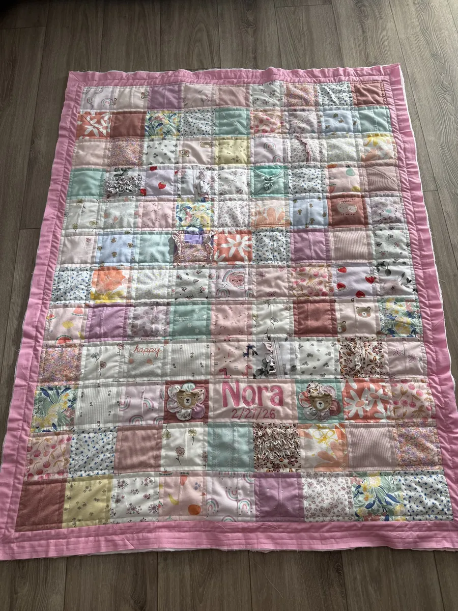 A memory quilt made from baby clothes, with the baby's name stitched in