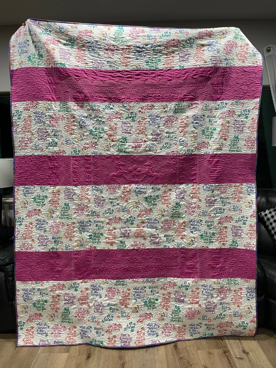 A pink striped quilt with floral fabric